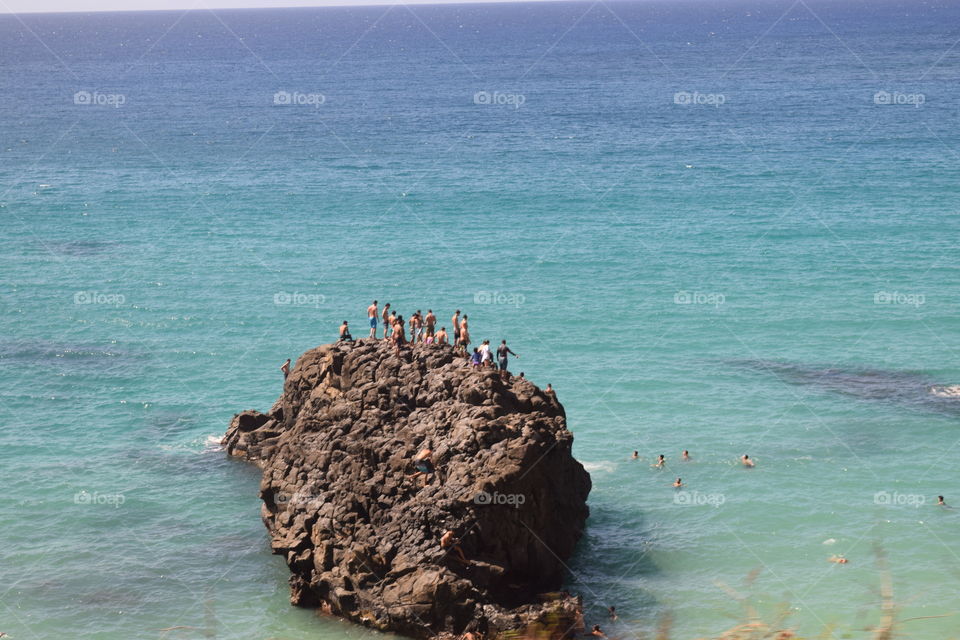 People jumping off a rock in Hawaii