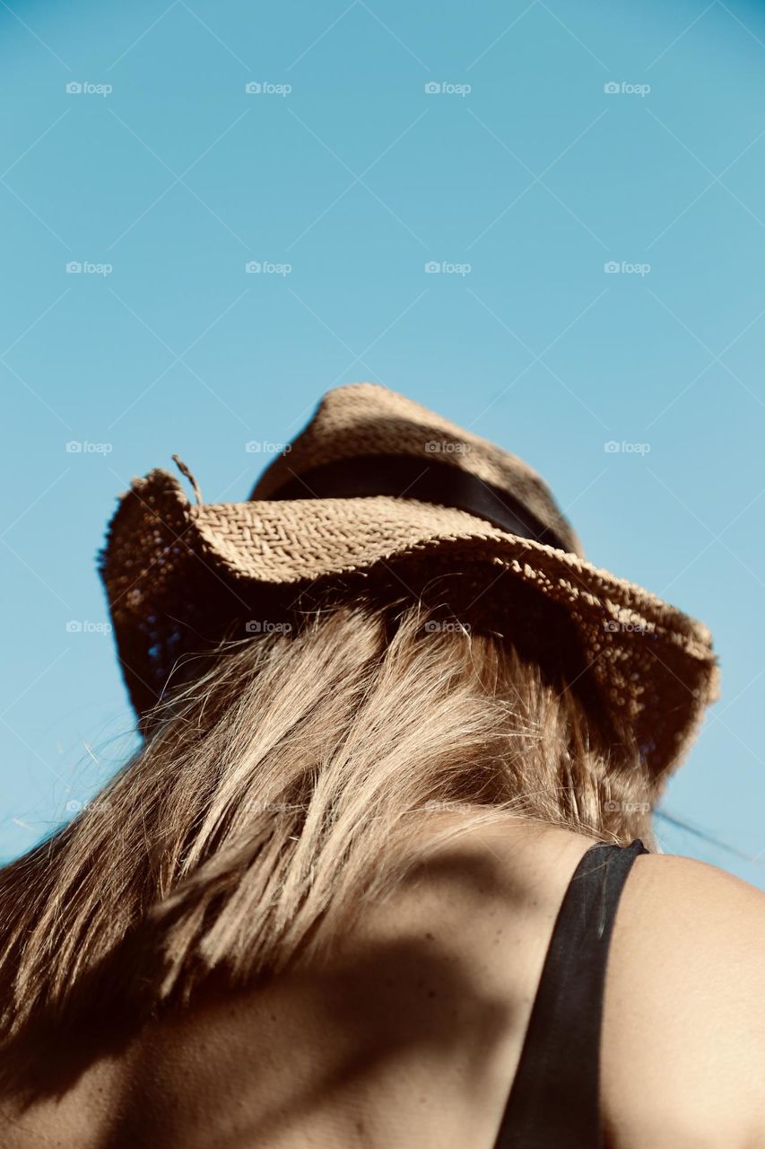 Sunshine and woman with brown hair wearing a straw hat 