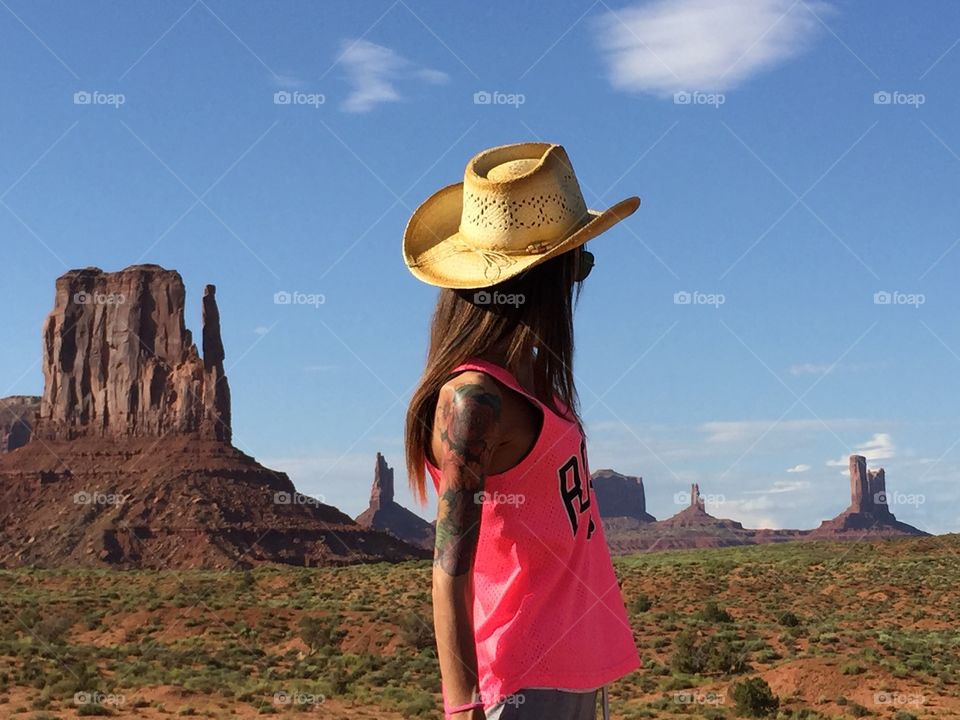 A young woman cowboy stand in the monument valley