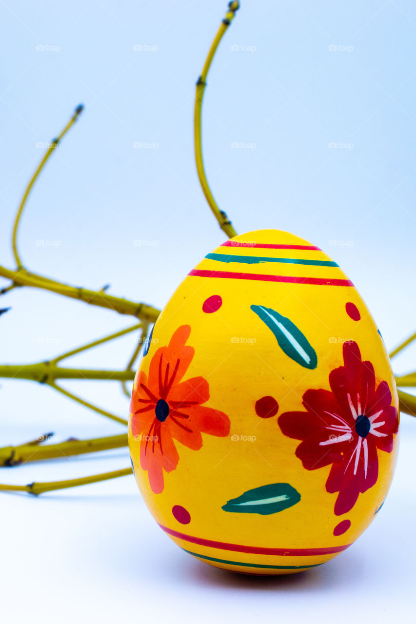Yellow wooden hand-printed Easter egg on white background