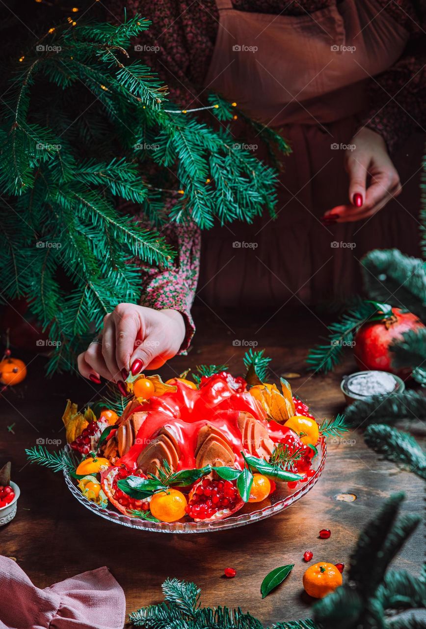 Christmas table setting. Bundt cake pudding sprinkled with sugar powder decorated with pomegranate and tangerines. High quality photo