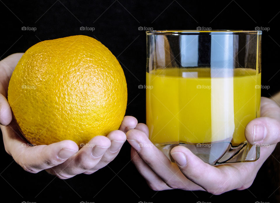 Woman holding orange and glass of orange juice