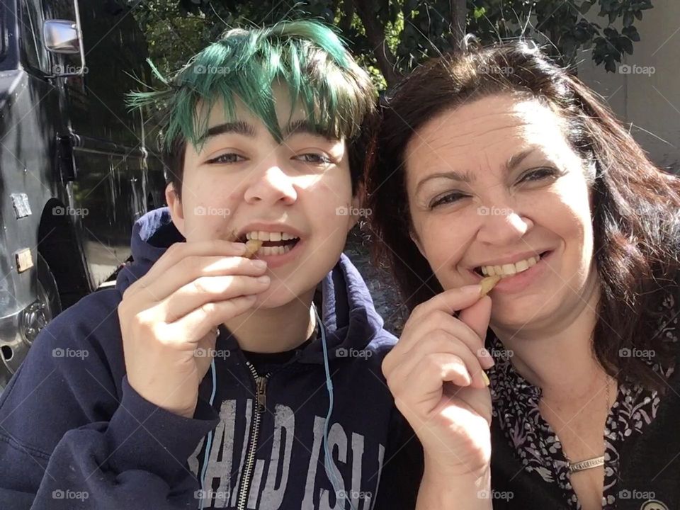 Mother and son eating French fries together 