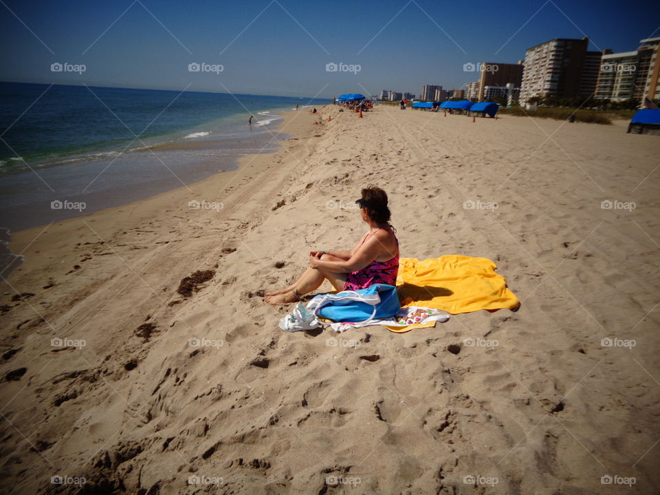 Woman enjoying ocean & beach lined with hotels.