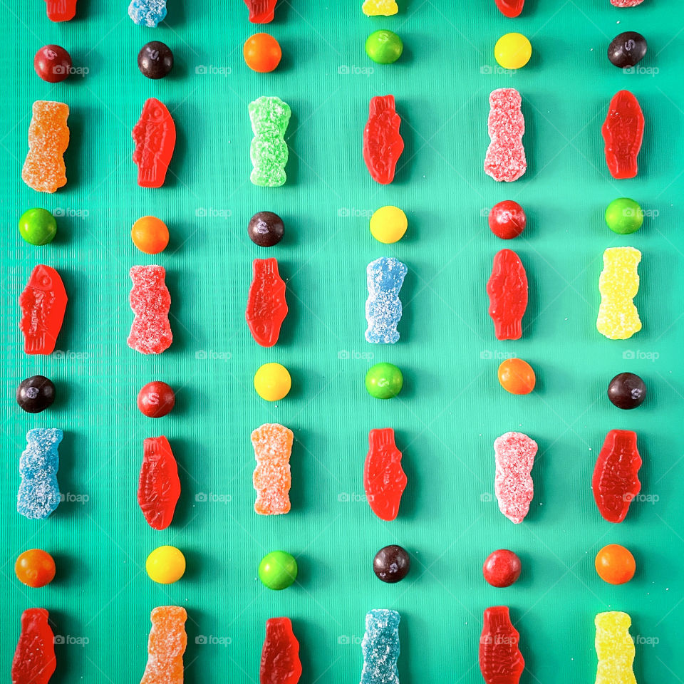 Bright pattern made of gummy candy on aqua background 