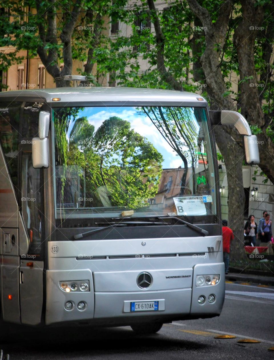 Bus stop reflections. Beautiful trees and sky reflect off the curved windshield of a city bus 