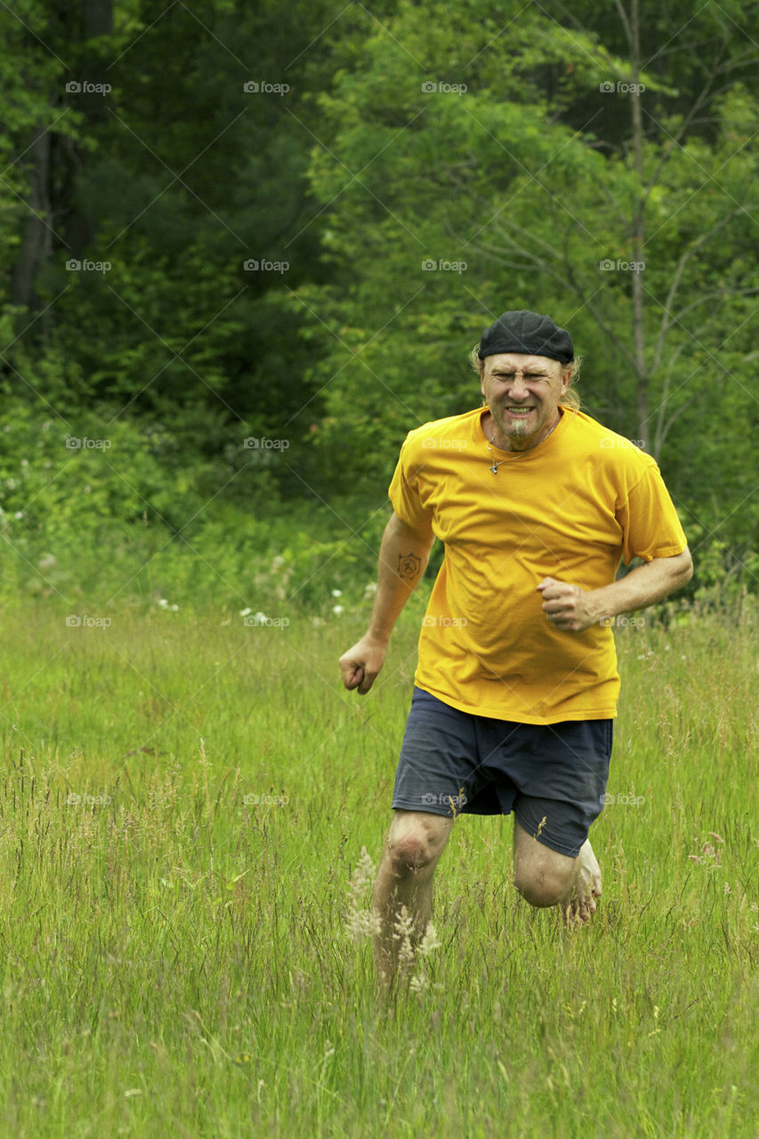 Mature man running on green grass