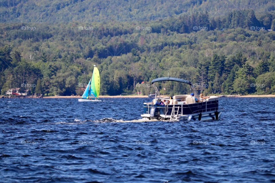 Sailboat and flat bottomed lake boat on Chateaugay Lake in the Adirondack mountains of New York State 