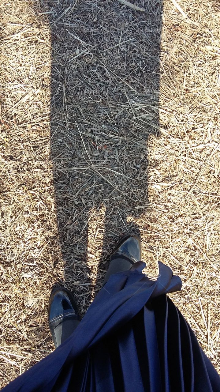 фото сверху юбки и обуви девушки на желтой траве