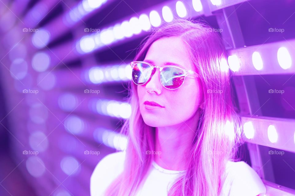 Woman with eyeglasses standing in tunnel with purple neon light 