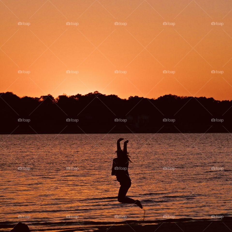 World of silhouettes and shadows -  A Girl jumps for joy in a silhouette against a bright orange sunset