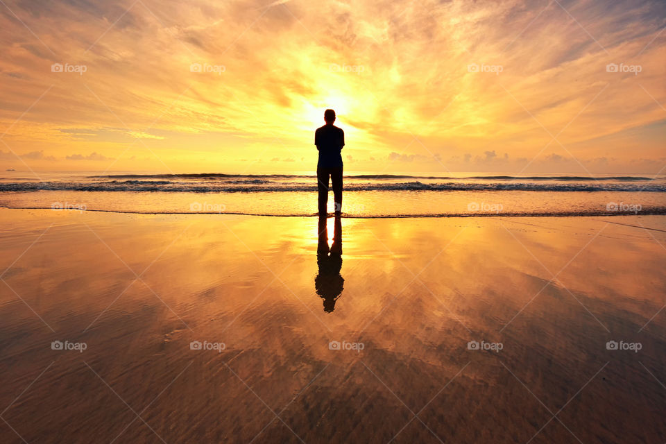 Man standing alone on the beach during sunset