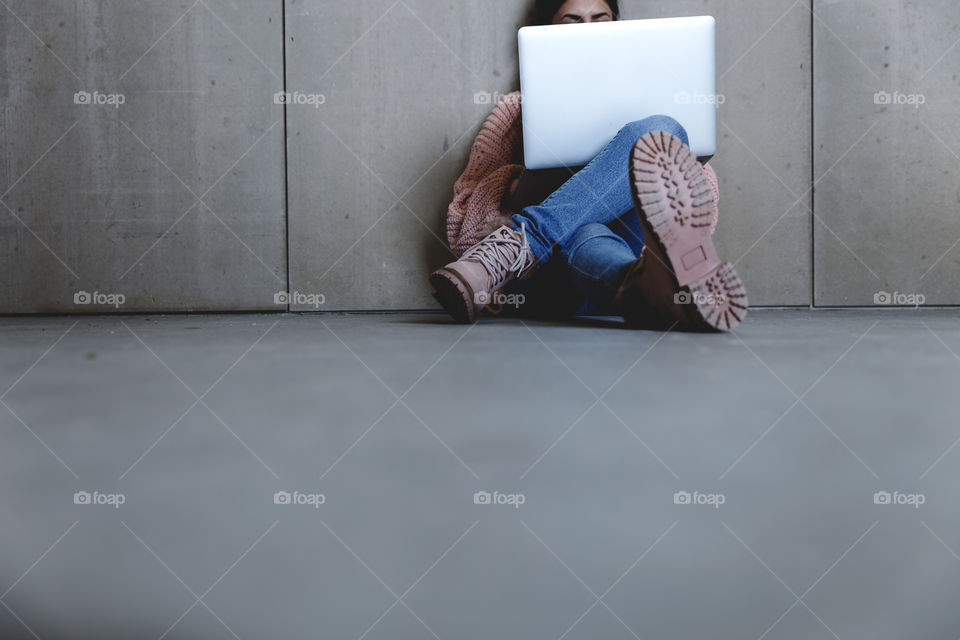 A female sitting on the floor and using laptop 