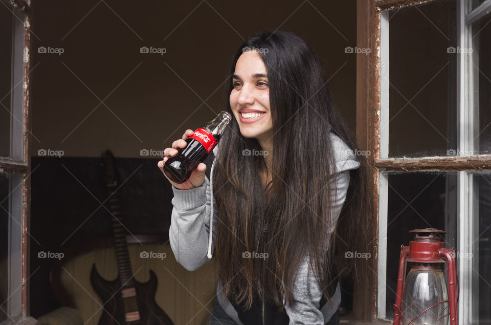 Beautiful woman drinking Coca-Cola on the window