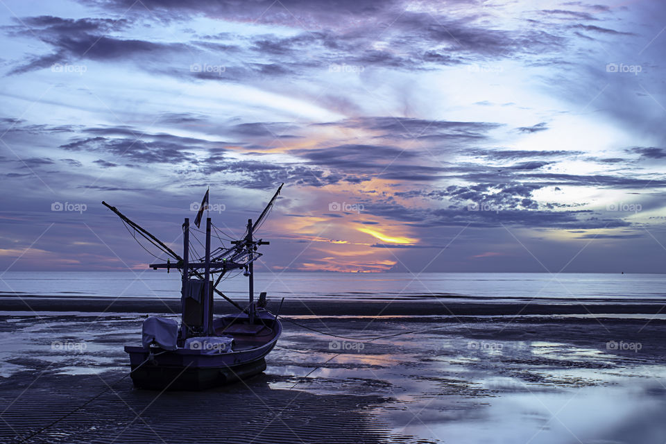 The morning sun light in the sea and the boat on the beach.