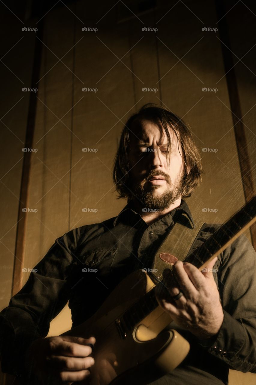 Bearded man playing electric guitar. Long haired man playing rock and roll guitar