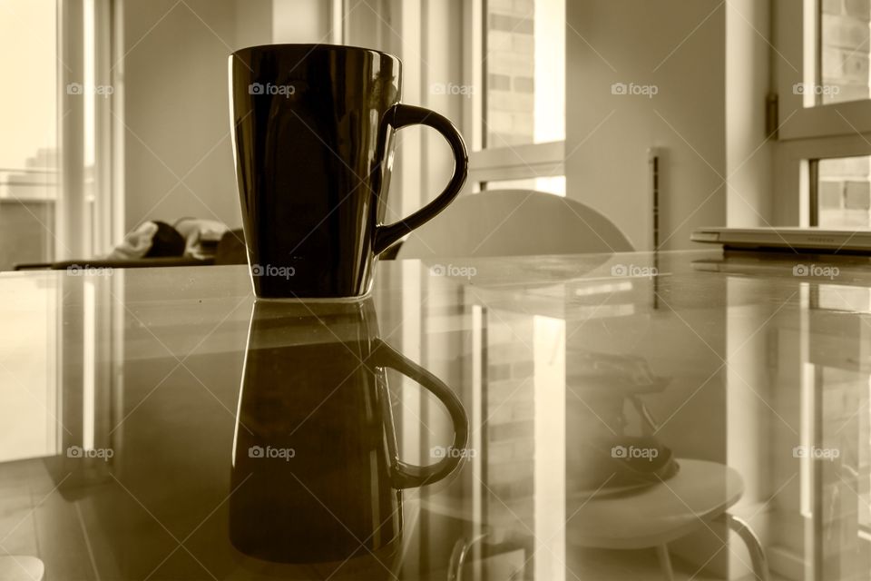 Coffee cup and reflection on the glass table