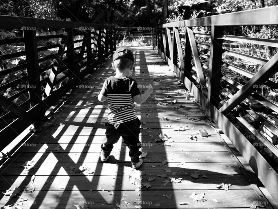 Toddler walking across bridge black and white 