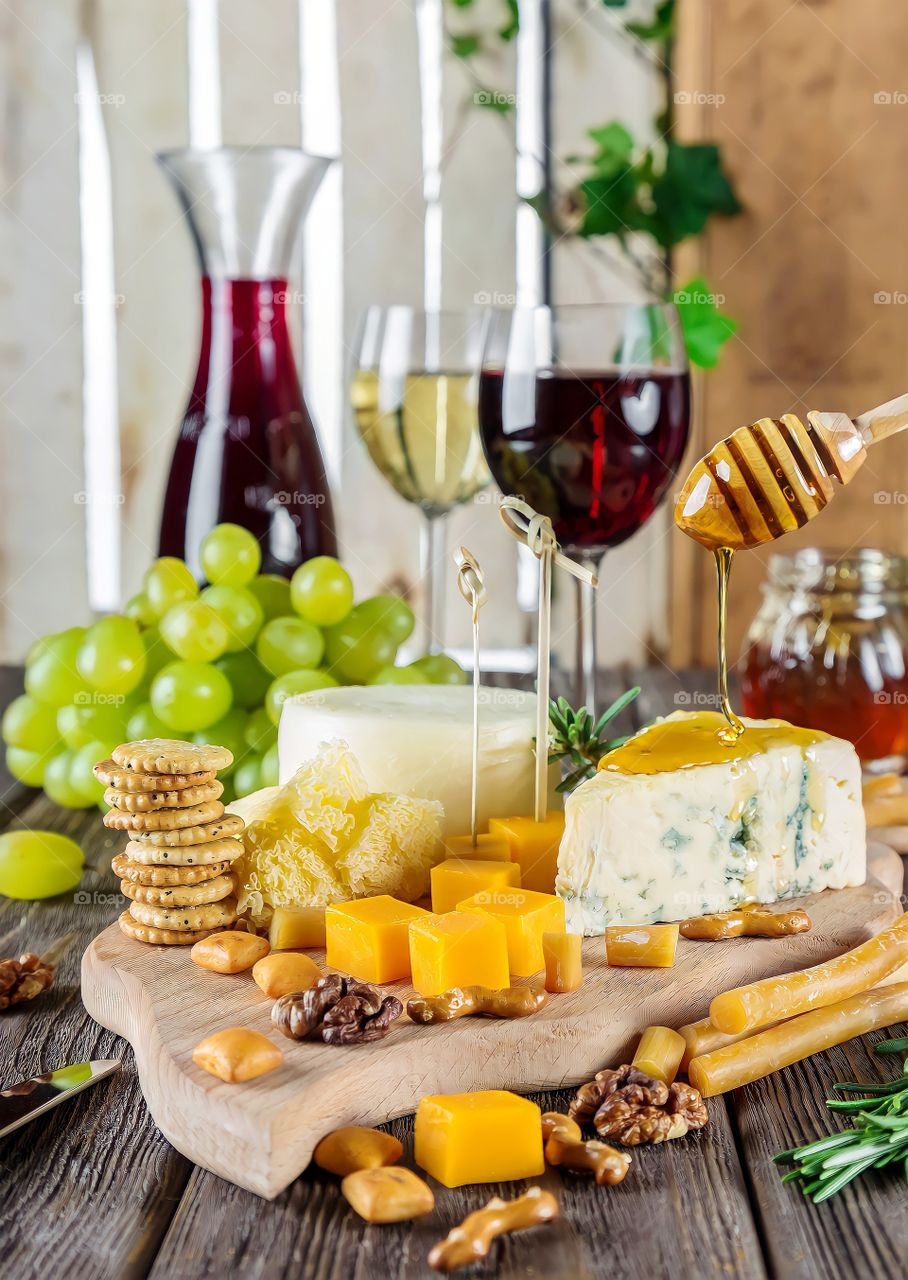 Cheese Plate
Cheese with fresh grapes, cookies and glasses of wine on wooden board.