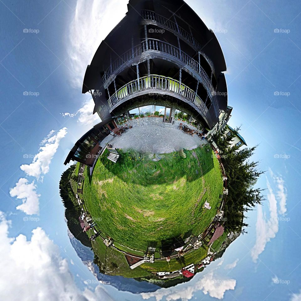 Fisheye lens of grassy landscape with house against sky