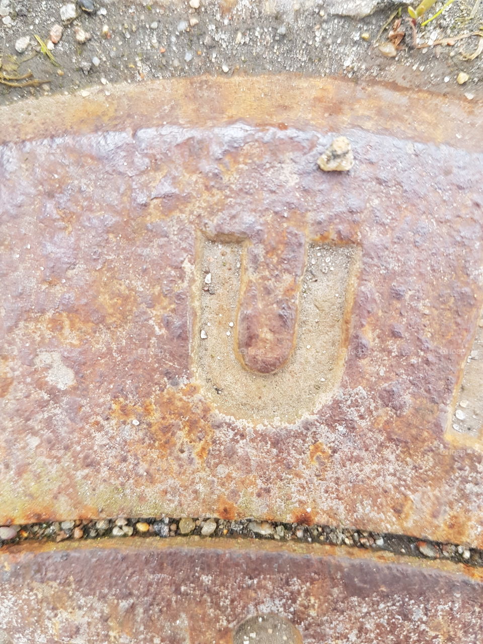 rusted letter U on manhole cover