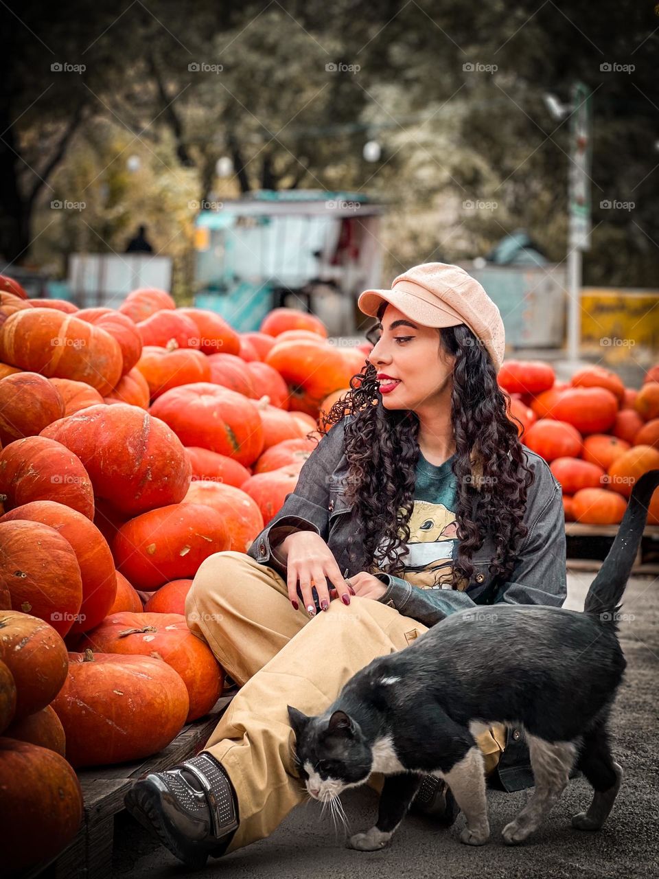 A girl with curly hair among pumpkins and a cat with feelings