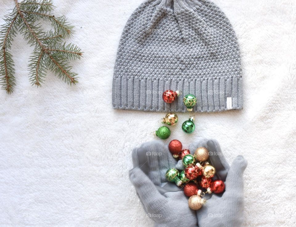 Still wow a woman wearing grey gloves holding small Christmas bulbs, grey hat