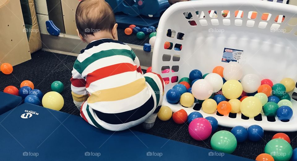 Toddler playing with plastic toy balls