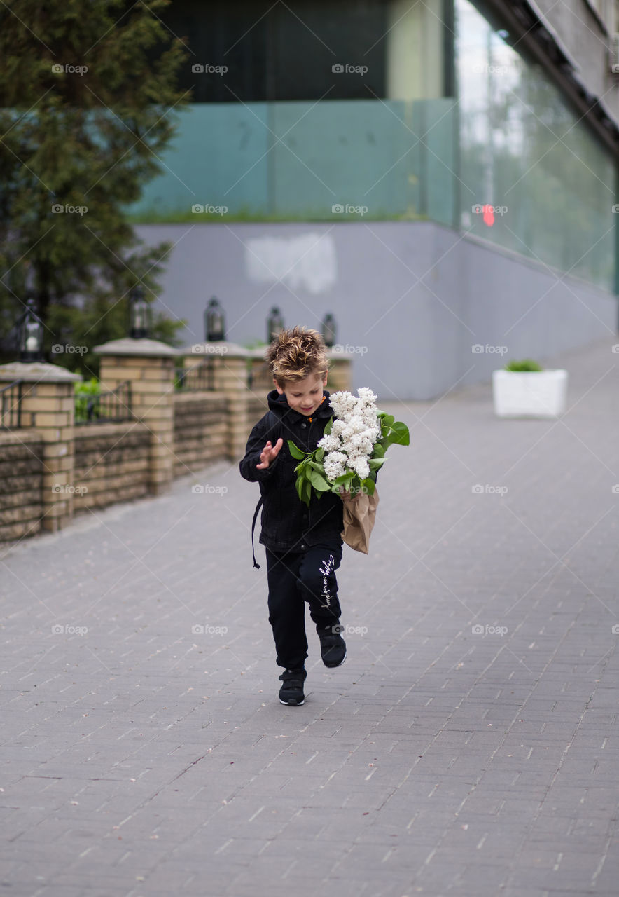 stylish boy in black clothes and glasses is walking along the street.  baby five years old, beautiful blond