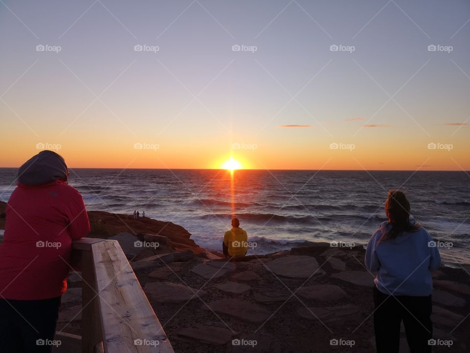 Three people watching the sunset. Îles-de-la-Madeleine, Québec, Canada.