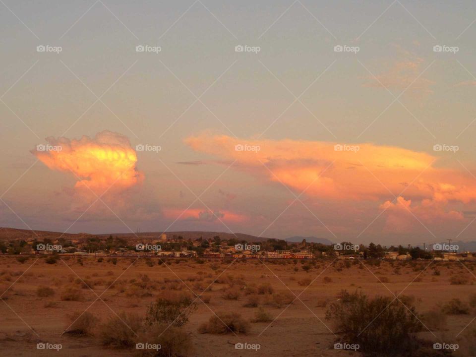 big clusters of clouds turned yellow and orange by the sunset in the desert