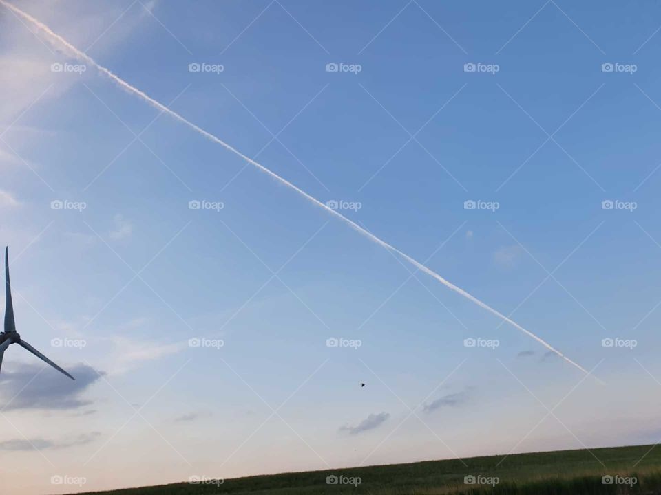 High in the still blue sky with some clouds. From early evening time, jet route. Nederland - Zuid-Holland.