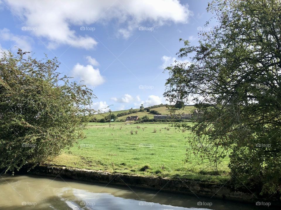 Late morning narrowboat cruise on Oxford canal past Willoughy near Onley before Barby clear sunny sky lovely late summer weather vacation holiday English country field farm clouds bank