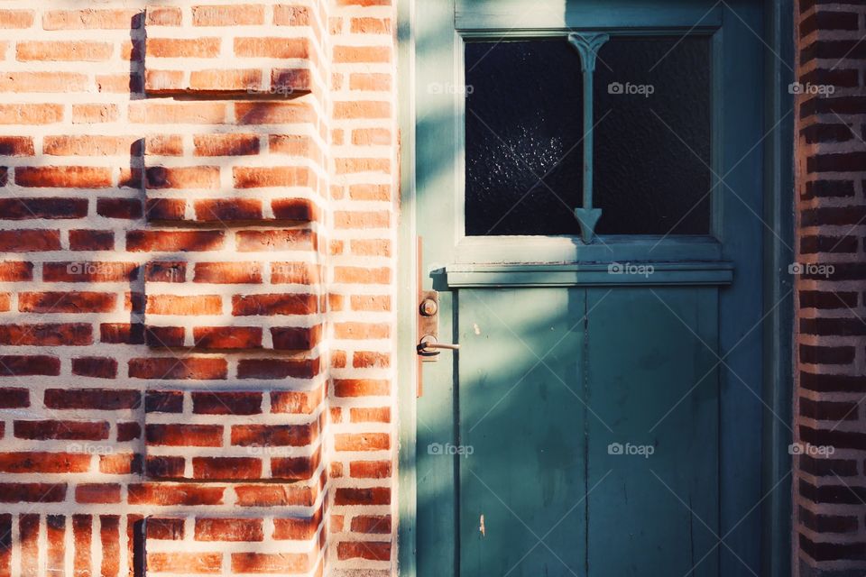 Shadow and light on brick wall and green wooden door 