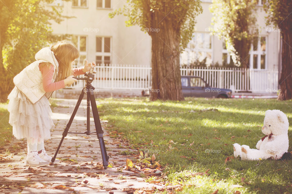 little girl photographer. little girl trying to capture her big teddy bear with her camera