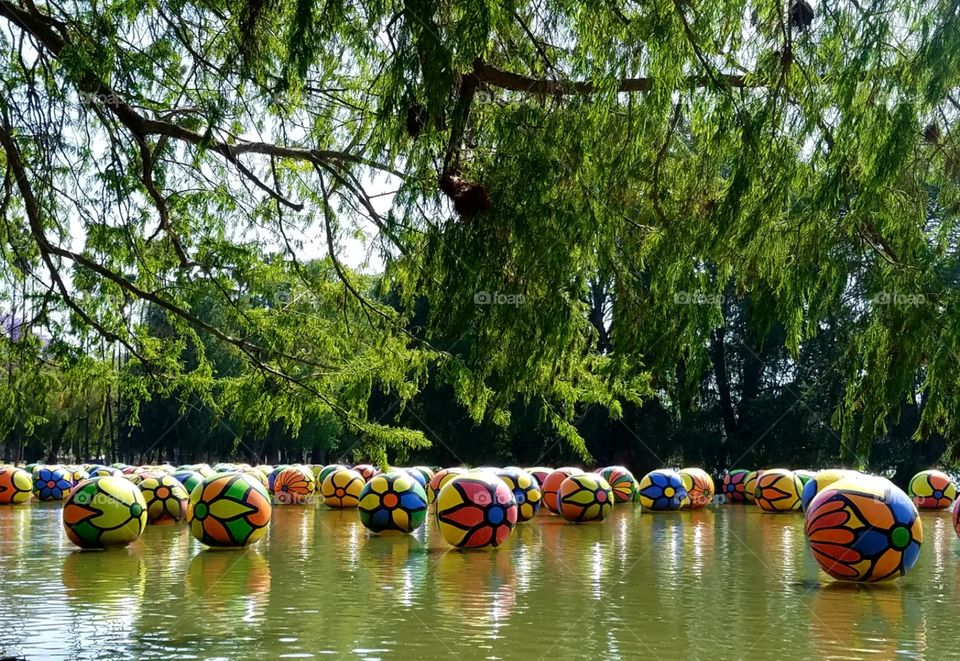 floating colored balls on water surrounded by trees at fairmount park riverside California