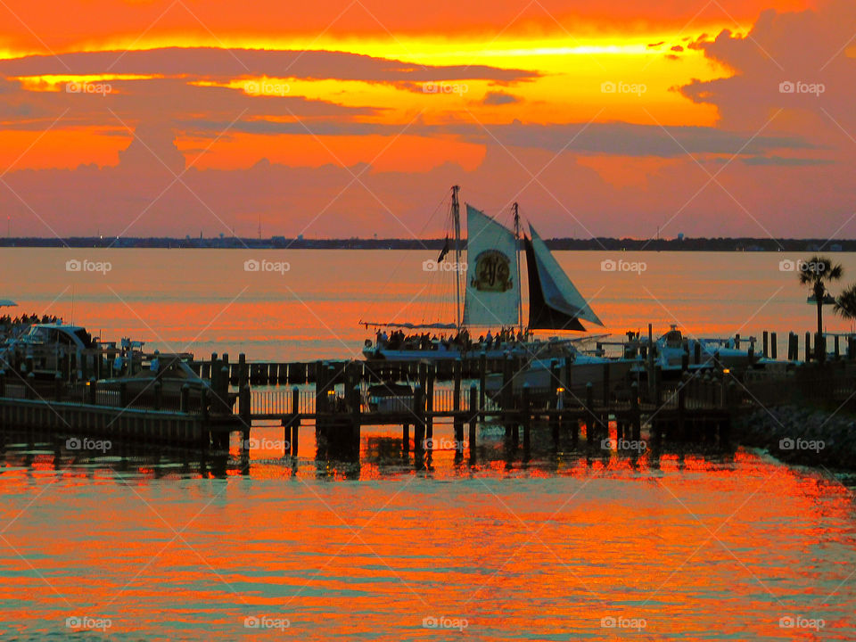 Sailing in the sunset! A sailboat filled with tourist cruises along the shoreline of the Choctawhatchee Bay as they are mesmerized by the sunset reflection!