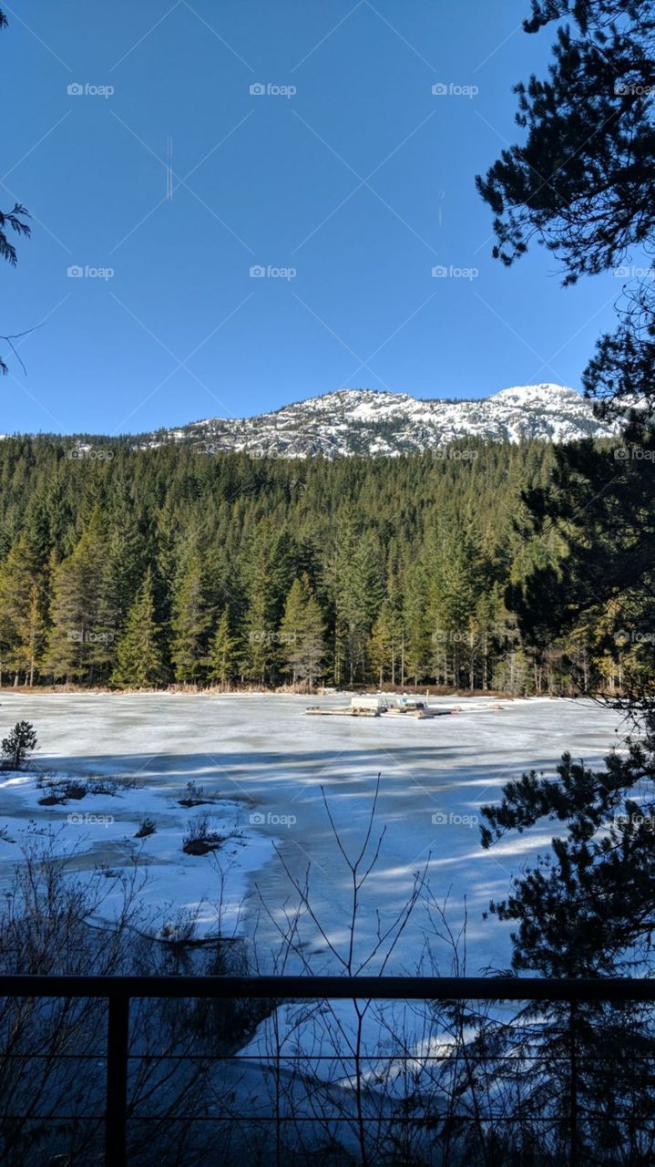 Lost Lake frozen over  in Whistler as the sun shines down to warm the surface