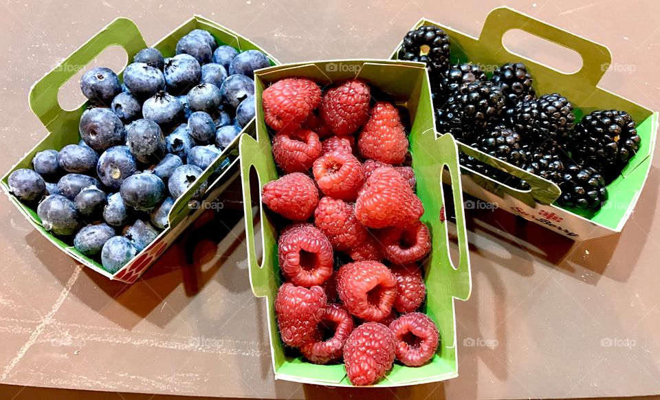 Raspberries, havkleberries and blackberries in the paper basket on a market