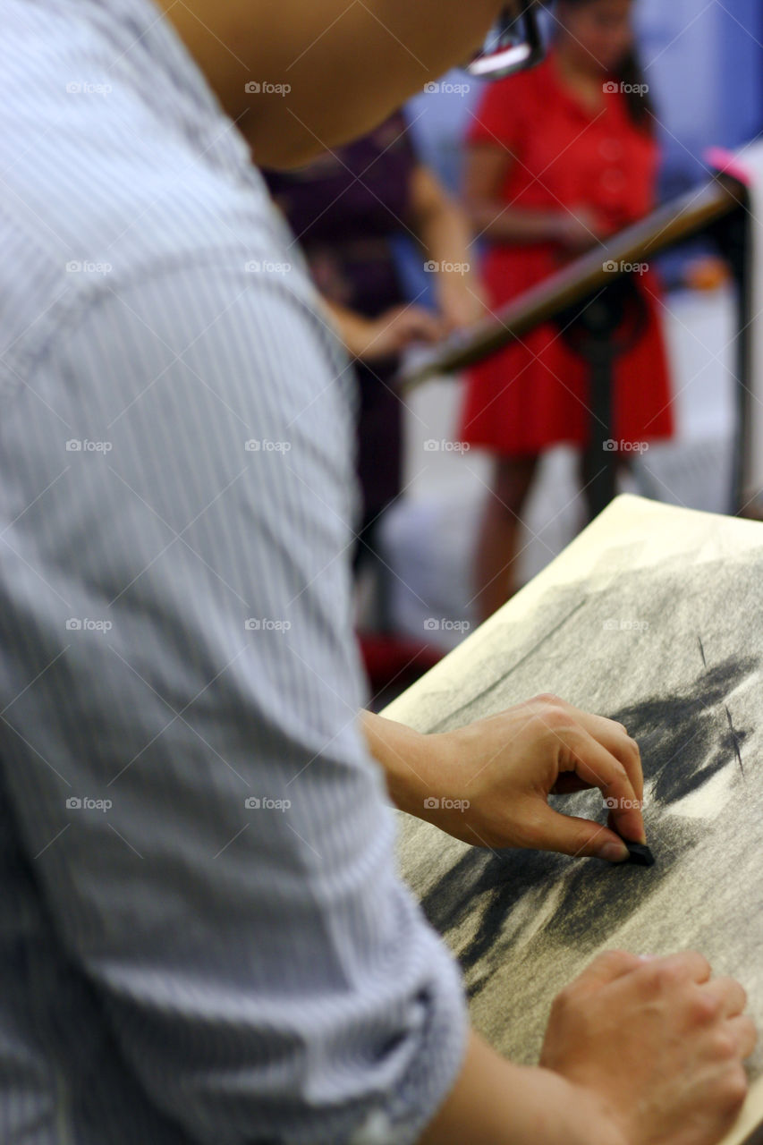A man sketches a model in charcoal in the studio 