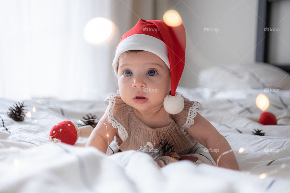 Little infant girl in santa’s red had