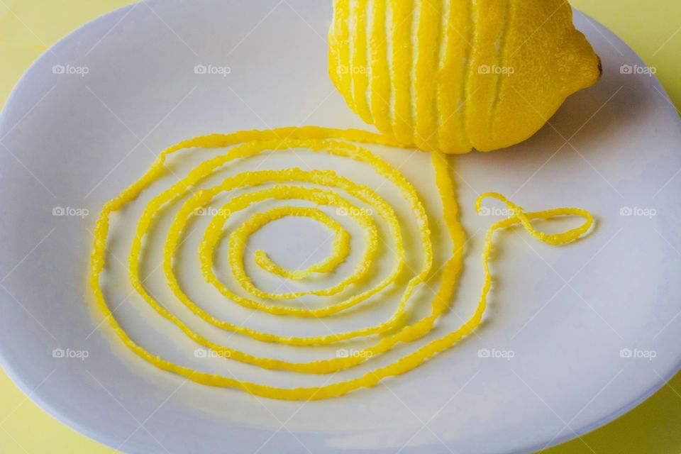 Fruits! - Lemon and spiraled lemon peel on a white plate with yellow background  