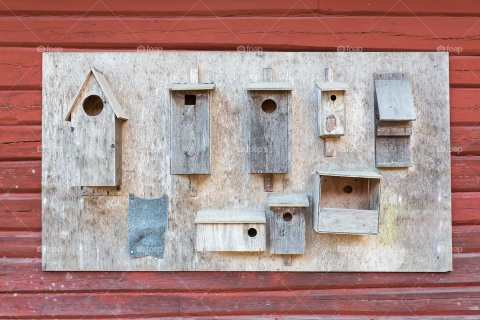 Wooden bird houses in different shapes and sizes on a red wooden wall 