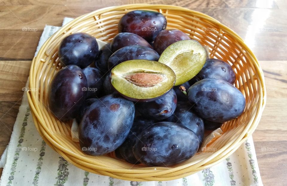 Plums in a bowl on wooden table