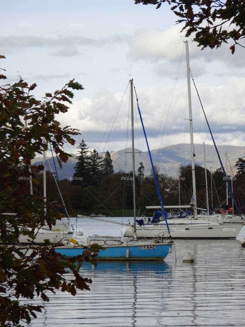 Lake Windermere with sail boats and the sun beaming down on the fells in the background. Lake Windermere is situated in Cumbria uk