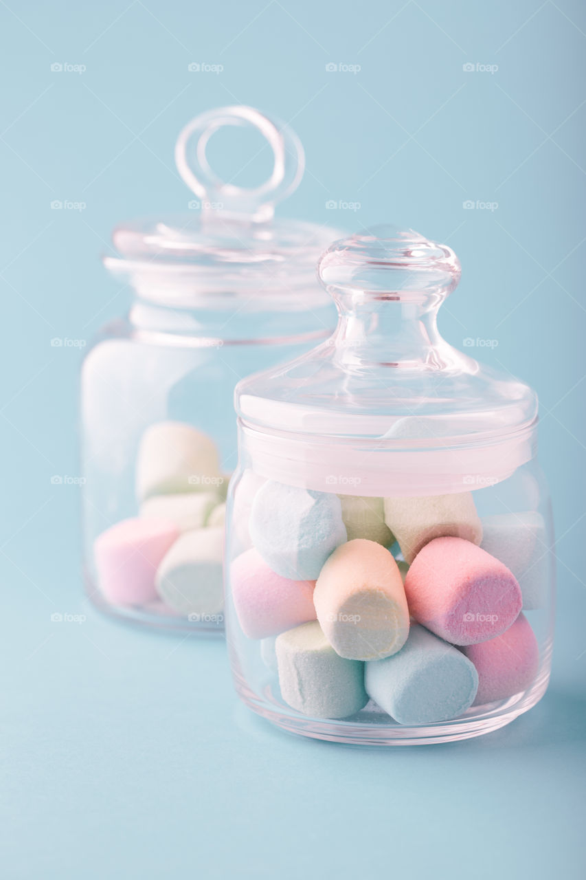 Jar filled with colorful marshmallows on plain background
