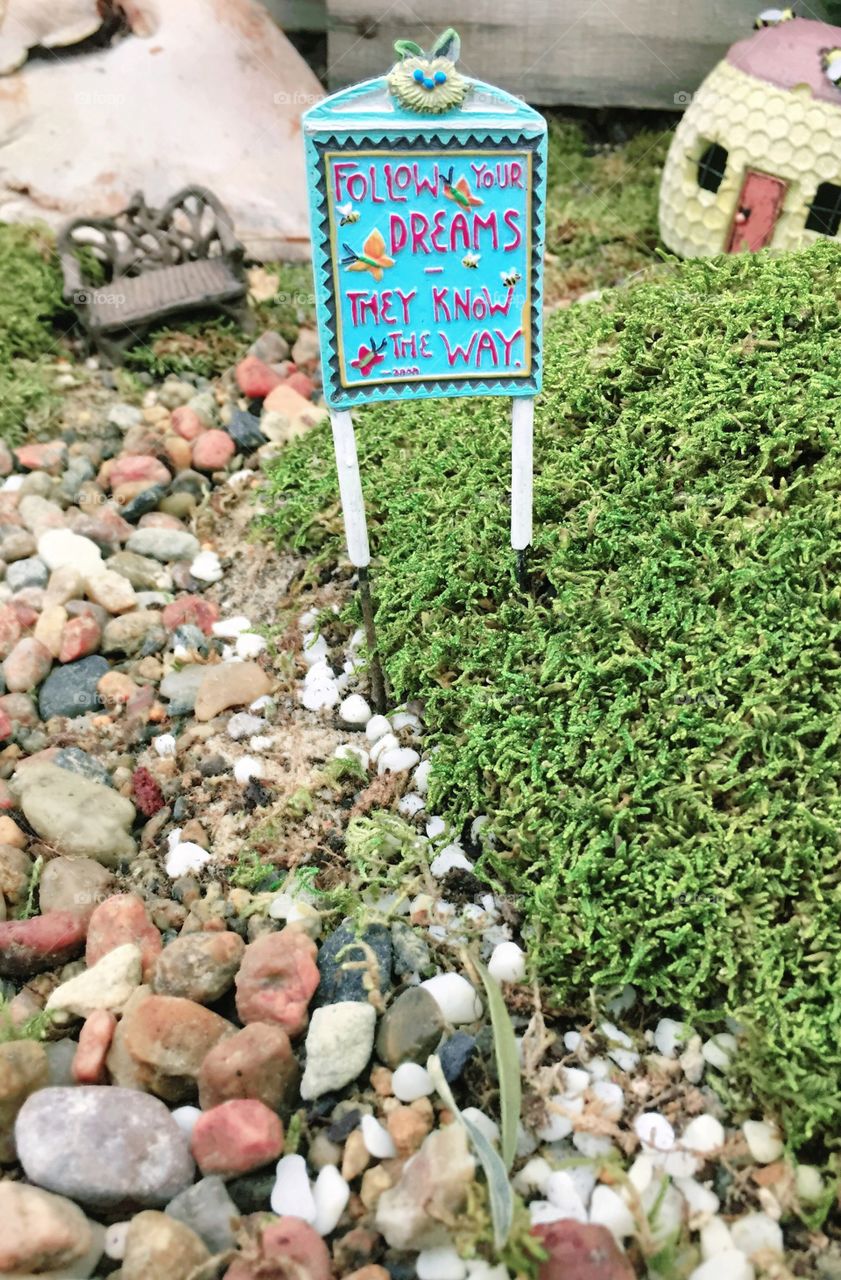 Mini Motivation - miniature scene of a stone walking path, metal bench, cottage, green foliage, turquoise porcelain sign posted along path with motivational message