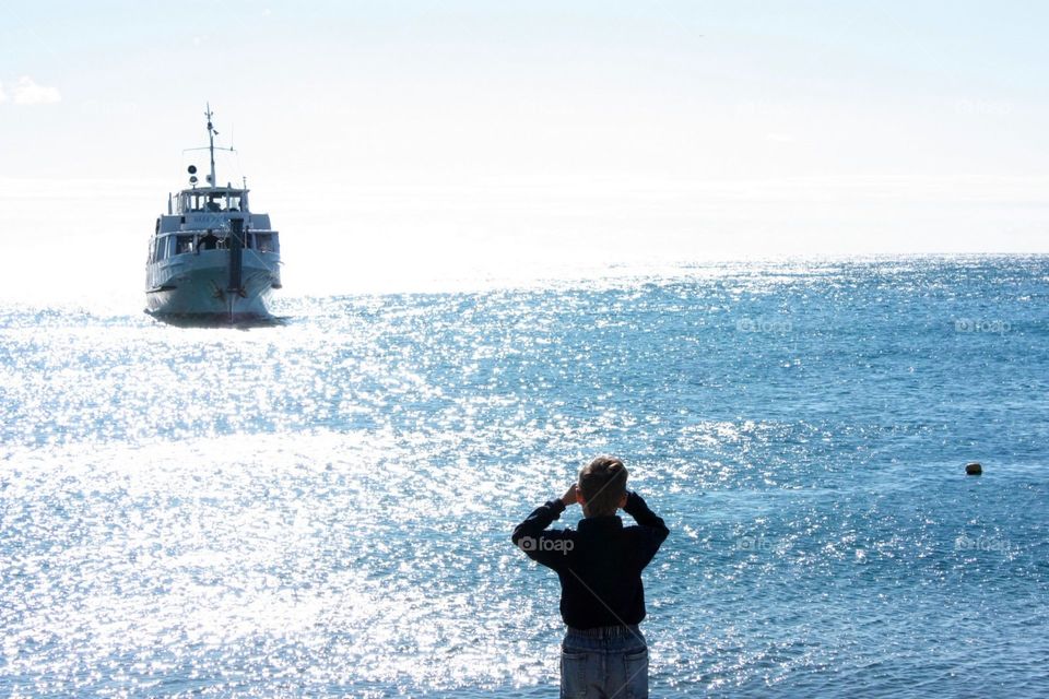 Boy looking at the ferry at the horizon 