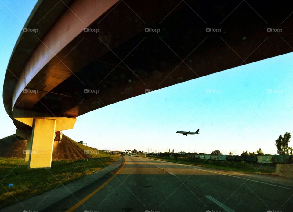 Plane being seen landing through a highway over pass