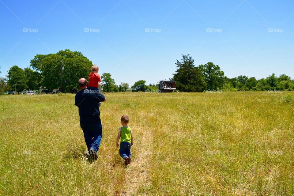 My husband and the grand boys walking in the hayfield together to go down to the pond in Maysfield Texas 